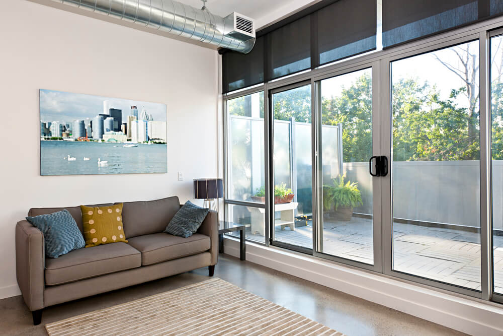 Living room with large impact sliding glass doors opening to a balcony, installed by STS Impact Windows & Doors
